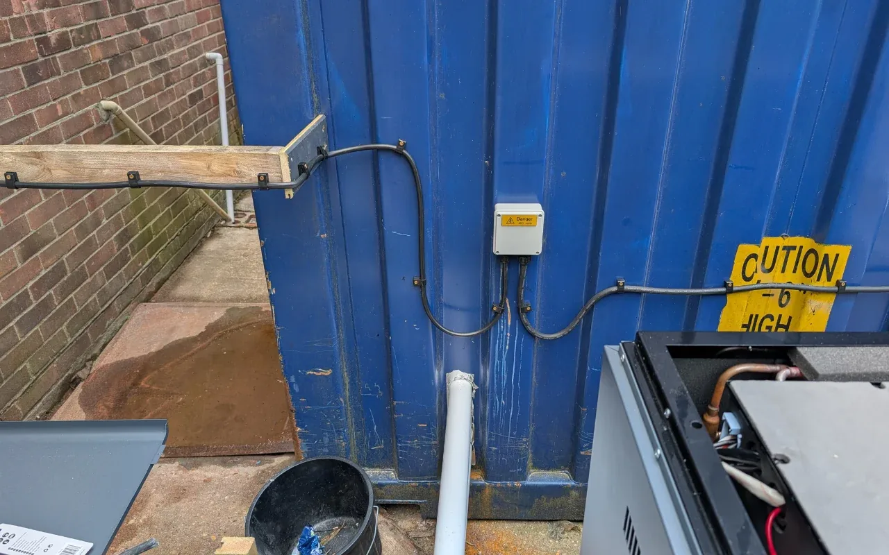 Weatherproof junction box fitted to an outbuilding